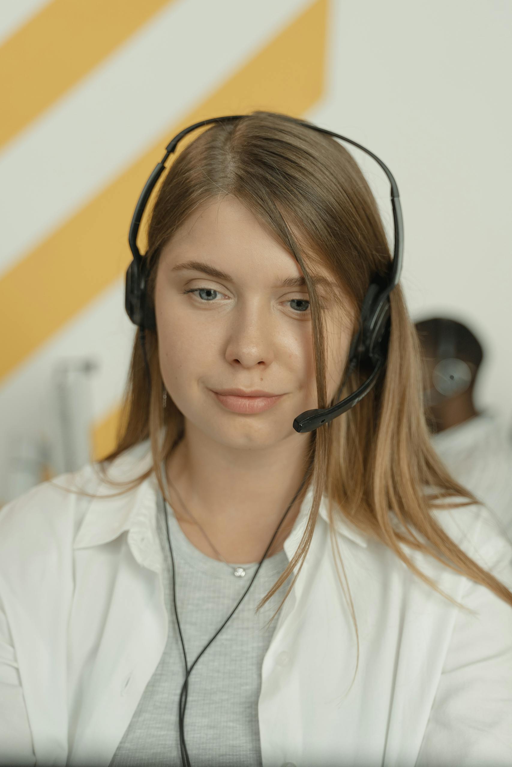 Professional woman wearing headphones, providing excellent customer service in a modern office setting.